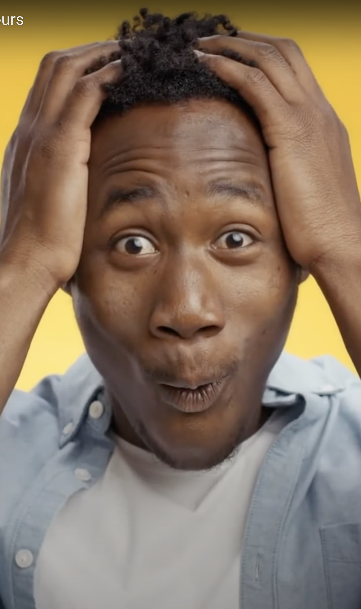black guy hands on hair with oh my god face with yellow background